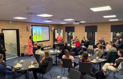 Työpajan osallistujia seuraamassa koulutusta pöytäryhmissään.