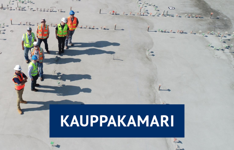 Kauppakamarin logo ja työasuisia henkilöitä rakennustyömaalla ilmasta kuvattuna.