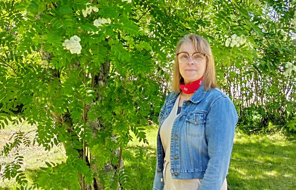 Sirpa Vauhkala kuvattuna kukkivan pihlajan vieressä.